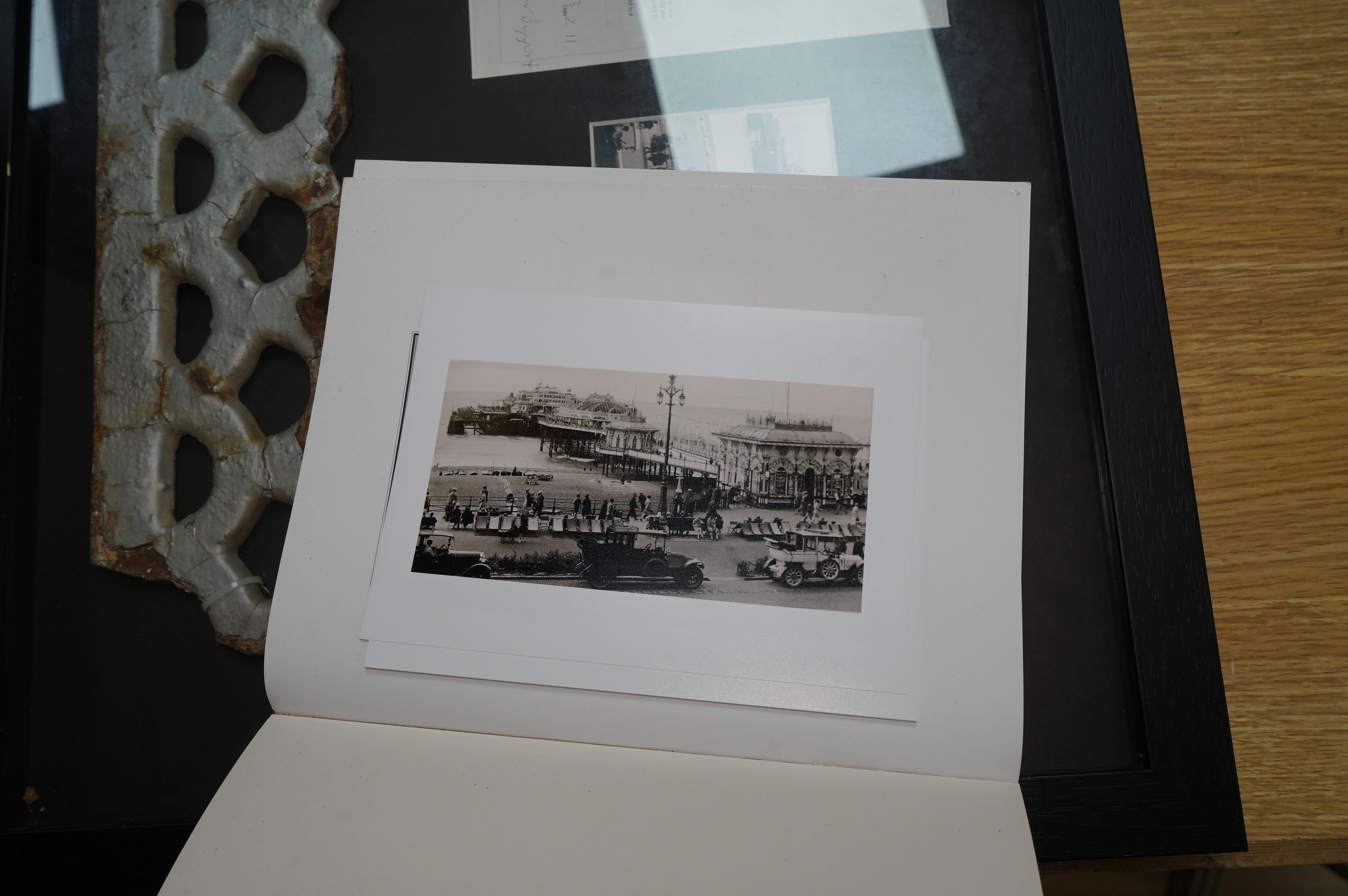 A framed part of the original frieze from the West Pier in Brighton, a photo and certificate, plus a book about the West Pier, 50cm wide, 40cm high. Condition - good